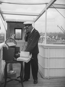 A ship's officer on the bridge uses a portable telephone connected to a land line, c1945-c1965. Artist: SW Rawlings