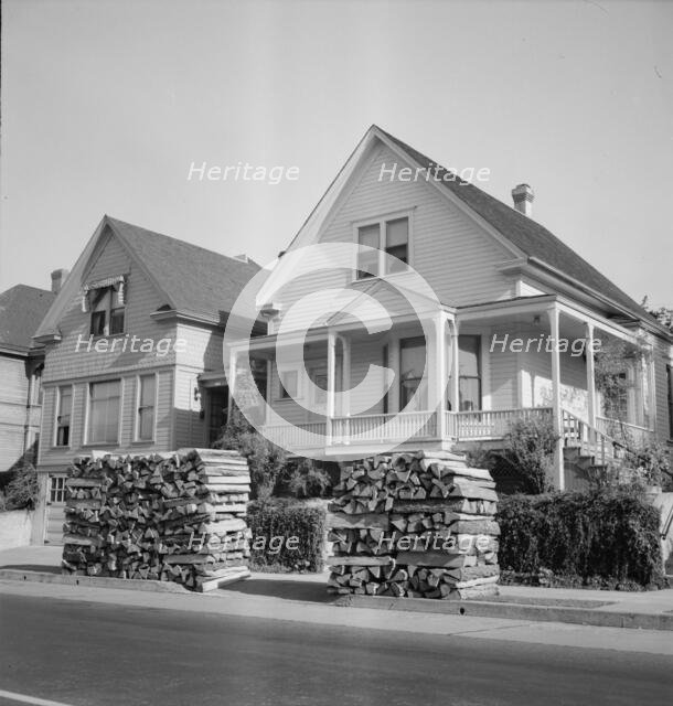 Woodpiles along the street are a characteristic of Portland, Oregon, 1939. Creator: Dorothea Lange.