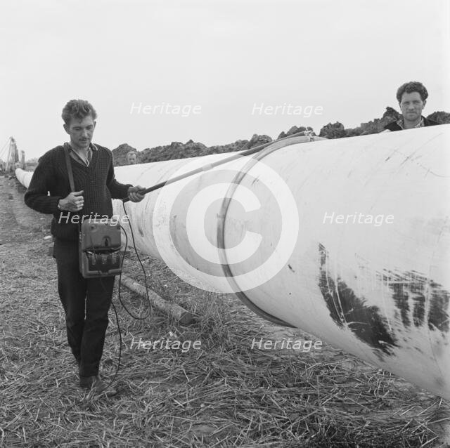 A worker walking along a section of the Fens gas pipeline, Norfolk, 24/07/1967. Creator: John Laing plc.