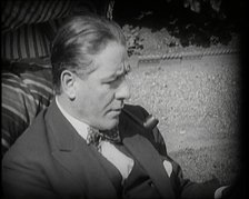 Matheson Lang Relaxing in a Deck Chair Smoking a Pipe, 1920s. Creator: British Pathe Ltd.