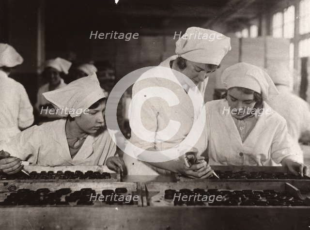 A girl is taught how to hand-pipe chocolates, Rowntree factory, York, Yorkshire, 1933. Artist: Unknown