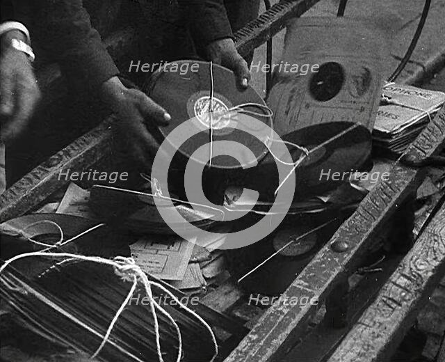 A Man Dumping Old gramophone records to Use for War Materials, 1942. Creator: British Pathe Ltd.