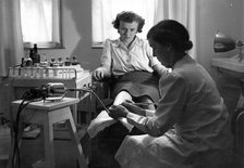 A Rowntree’s chiropodist works on a woman’s foot, York, Yorkshire, 1946. Artist: Unknown