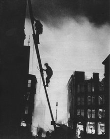 'Out in the Blitz, silhouetted aganinst the light of fires, rescue men climb into a building in St.  Artist: Unknown.