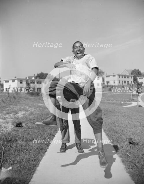 Boys playing leap frog near the project, Frederick Douglass housing project, Anacostia, D.C., 1942. Creator: Gordon Parks.