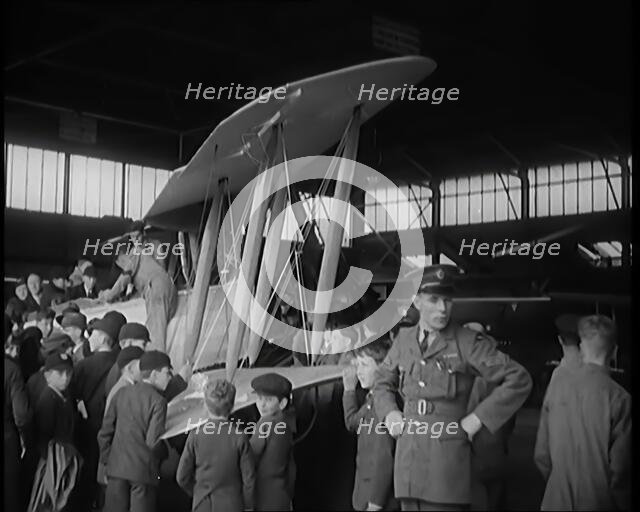 An RAF Officer Showing a Group of Male Children His Aeroplane, 1931. Creator: British Pathe Ltd.