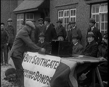 Men Buying Housing Bonds in Southgate. They Take a Piece of Paper from a Box on the Table..., 1921. Creator: British Pathe Ltd.