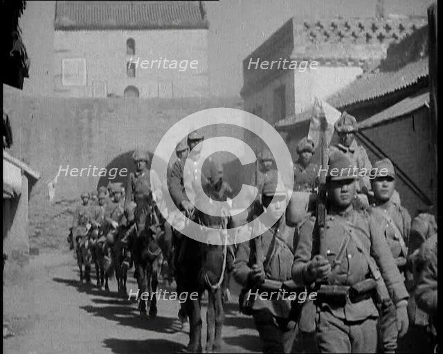 Japanese Soldiers Marching and Riding On Horseback Under an Arch and Through a Street..., 1937. Creator: British Pathe Ltd.