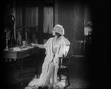 Female Civilian Seating in Front of a Dressing Table Wearing a Nightgown and Boudoir Cap, 1920. Creator: British Pathe Ltd.