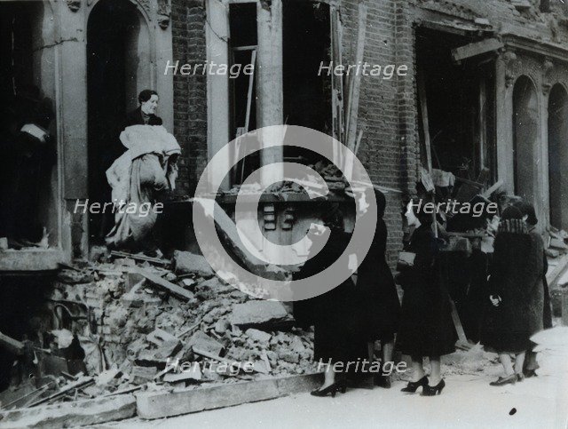 A woman collects her belongings from a bombed house, London, World War II, c1940-c1945. Artist: Unknown