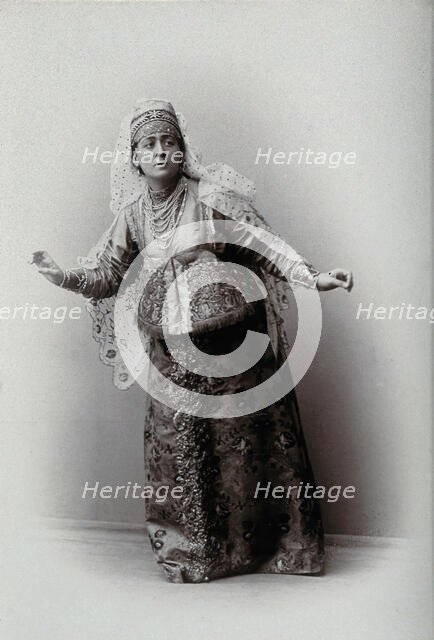 A woman posing in a photographic studio, wearing an embriodered dress, c1900s. Creator: Unknown.