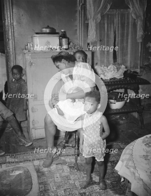 A mother getting the children ready for a neighborhood birthday party,Washington, D.C., 1942. Creator: Gordon Parks.