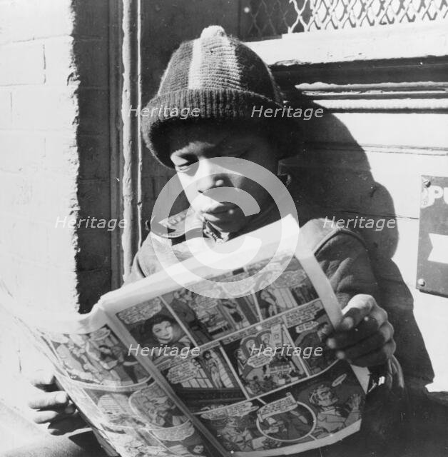 Negro youth reading a funny paper on a door step in the Southwest section, Washington, D.C., 1942. Creator: Gordon Parks.