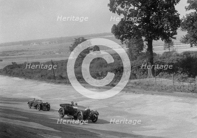 Bentley of FE Elgood and MG Magna of MB Watson racing at a MCC meeting, Brooklands, Surrey, 1933. Artist: Bill Brunell.