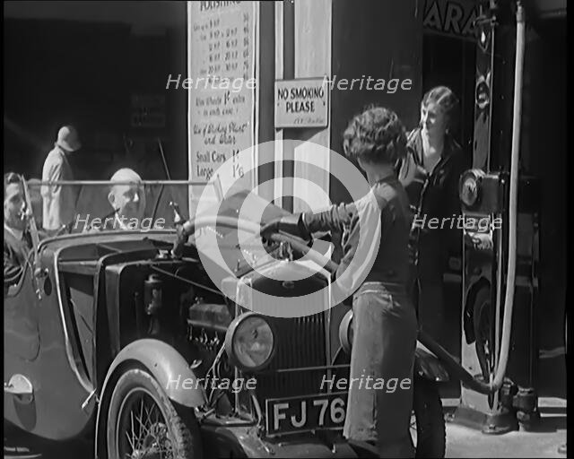 Female Civilians Working Petrol Pumps in a Garage and Filling up a Car, 1931. Creator: British Pathe Ltd.