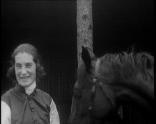 A Female Civilian Wearing a Jockey's Outfit Removing Her Hat in Front of Her Horse and..., 1920. Creator: British Pathe Ltd.