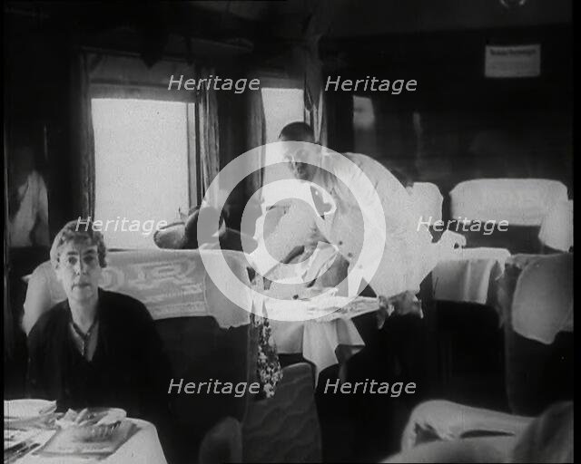 Passengers Sitting in the Dining Car of a Train as They Are Waited on by Attendants, 1938. Creator: British Pathe Ltd.