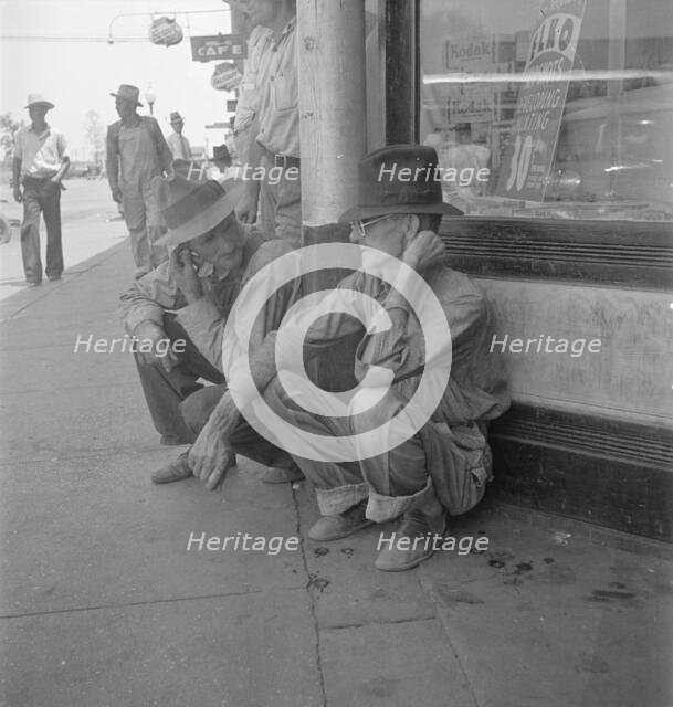 Drought farmers line the shady side of the main street of the town, Sallisaw, Oklahoma, 1936. Creator: Dorothea Lange.