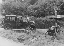 People relaxing by a signpost with a 1935 Standard 10 hp car, Devon, (c1935?). Artist: Unknown