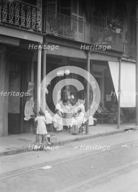 Women and children standing on a covered sidewalk, New Orleans, between 1920 and 1926. Creator: Arnold Genthe.
