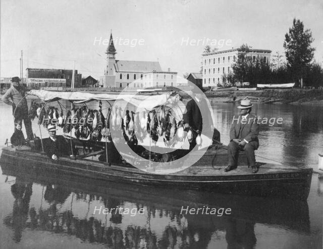 Marshall Erwin in front of a boat containing a kill of ducks, between c1900 and 1927. Creator: Unknown.