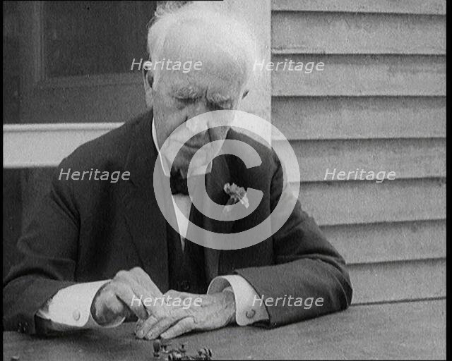 Thomas Edison Sitting at an Outside Desk and Operating a Morse Code Sender, 1921. Creator: British Pathe Ltd.