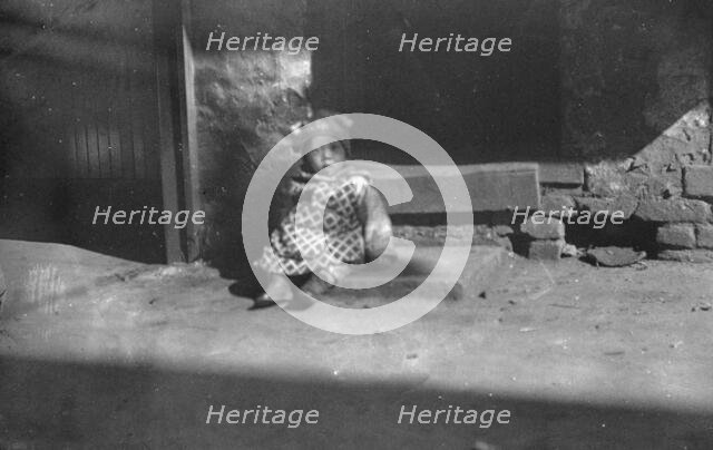Small child sitting on a doorstep, Chinatown, San Francisco, between 1896 and 1906. Creator: Arnold Genthe.