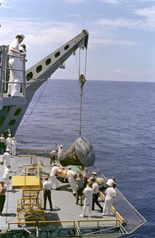 Gemini 5 capsule hoisted onboard recovery ship, 1965. Creator: NASA.