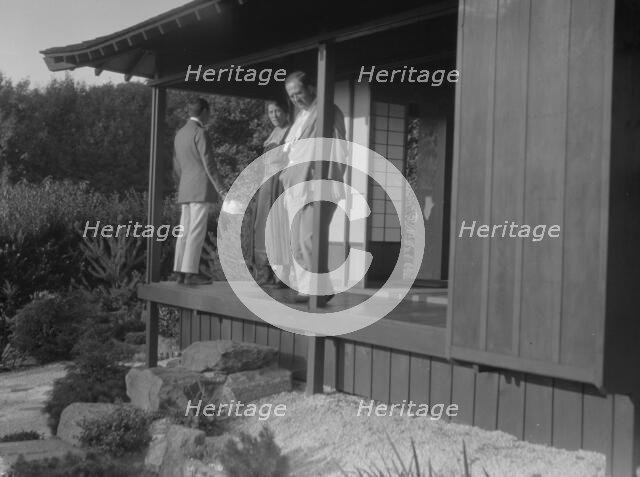 Three people standing on the porch of a Japanese-style building in a garden... A.W. Bahr, c1917-1934 Creator: Arnold Genthe.
