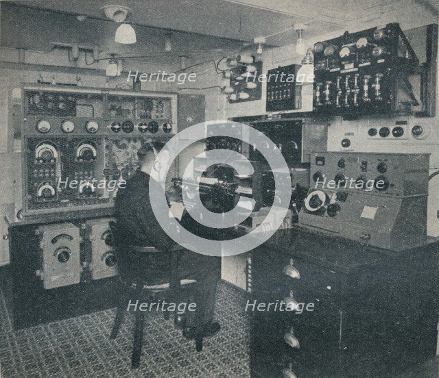 'A Marconi wireless operator receiving wireless messages as the Empress of Britain crosses the Atlan Artist: Unknown.