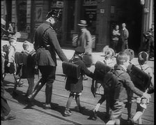 Man in Uniform Helping Young Children Cross the Road, 1933. Creator: British Pathe Ltd.