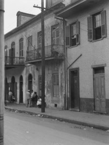 View from across street of four people talking in the French Quarter, New Orleans, c1920-1926. Creator: Arnold Genthe.