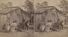 Family group sitting in front of a wooden shack, (1868-1900?). Creator: Unknown.