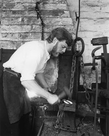 Black Country Museum, Birmingham, West Midlands, 1986. A blacksmith at work in a smithy.
