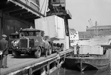A large crate is hoisted from a lorry onto a barge at the West Quay, Wapping, London, c1945-c1965. Artist: SW Rawlings