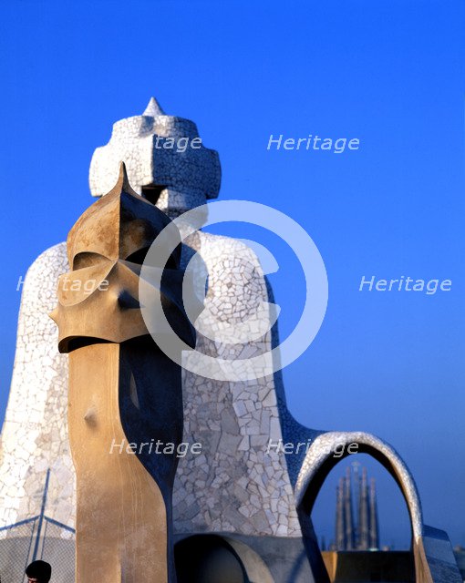Detail of the chimneys of La Pedrera or Mila House with the Sagrada Familia at background, work b…