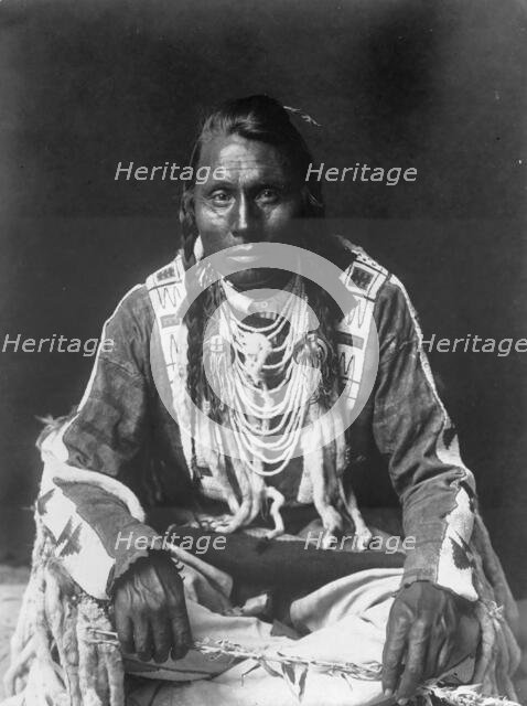 Wades in Water, Piegan Indian, full-length portrait, seated on floor, facing front..., c1910. Creator: Edward Sheriff Curtis.