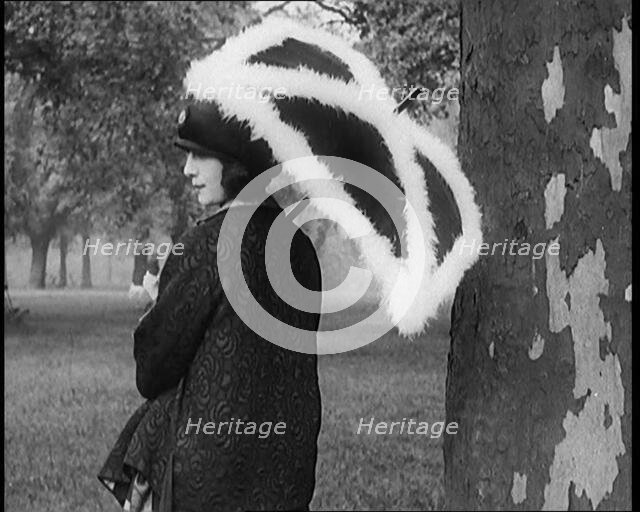 Female Civilian Dressed Glamorously Holding a Fur Trimmed Parasol in a Park, 1920. Creator: British Pathe Ltd.