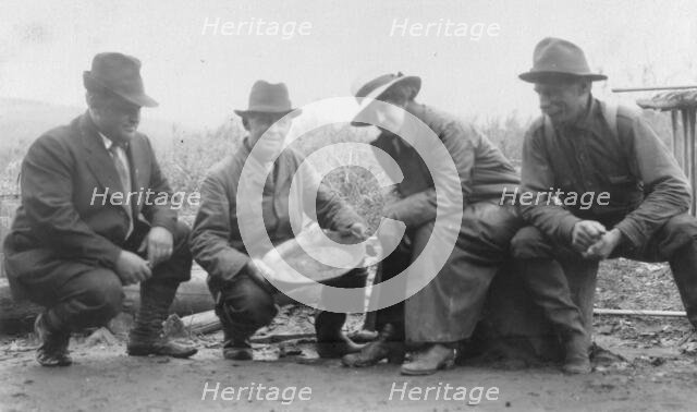 Group portrait of a woman and three men, crouched outside, smiling; one..., between c1900 and 1916. Creator: Unknown.