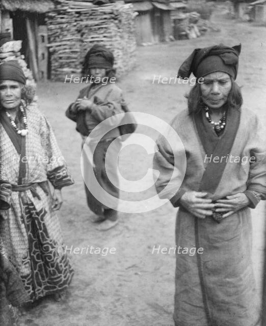 Three Ainu women outside in the village lane, 1908. Creator: Arnold Genthe.