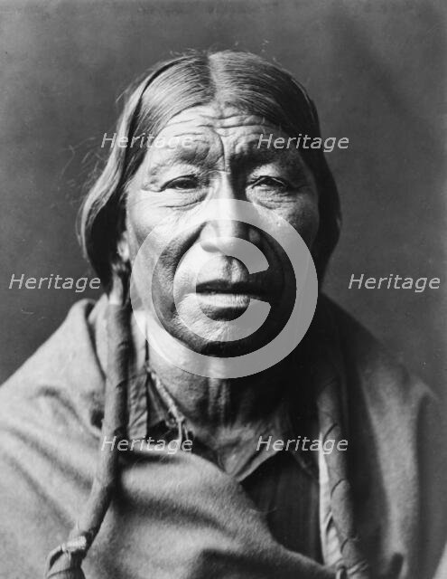 Cheyenne male, facing front, hair in wrapped braids, blanket around shoulders, c1910. Creator: Edward Sheriff Curtis.