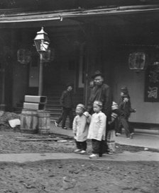 Man and two children crossing a street, Chinatown, San Francisco, between 1896 and 1906. Creator: Arnold Genthe.