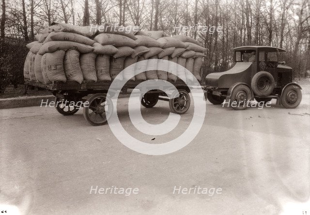 A tractor pulling a trailer loaded with sacks, 1928. Artist: Unknown