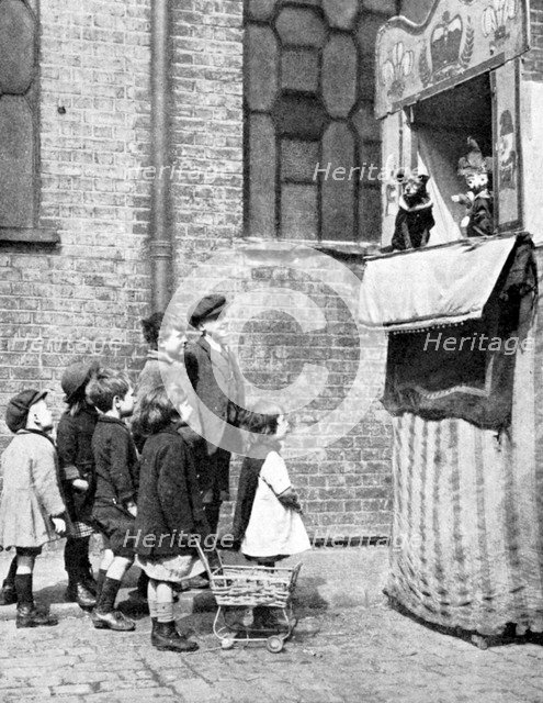 Children watching a Punch and Judy show in a London street, 1936. Artist: Donald McLeish