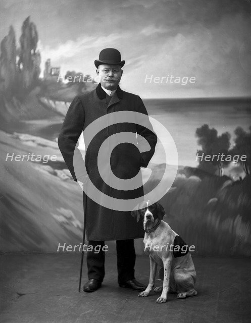 Elegant man wearing a black overcoat posing with his dog, Landskrona, Sweden, 1910. Artist: Unknown