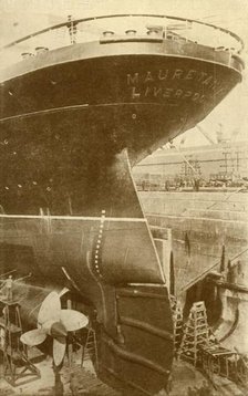 'At Work on the Stern of the "Mauretania", in Dry Dock', c1930. Creator: Unknown.