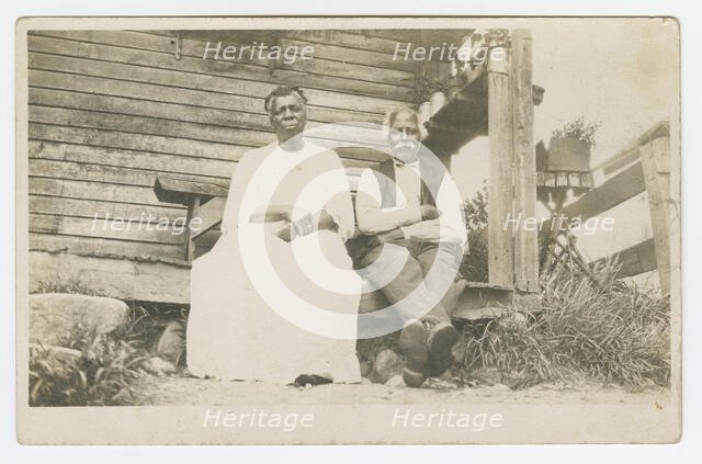 Photographic postcard of an elderly couple sitting on a porch, 1904-1929. Creator: Unknown.