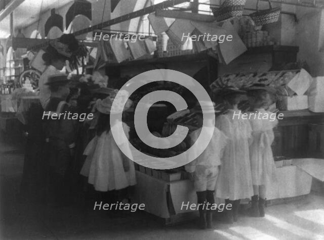 Woman schoolteacher and group of young pupils examining fruits and vegetab...Washington DC. (1899?). Creator: Frances Benjamin Johnston.