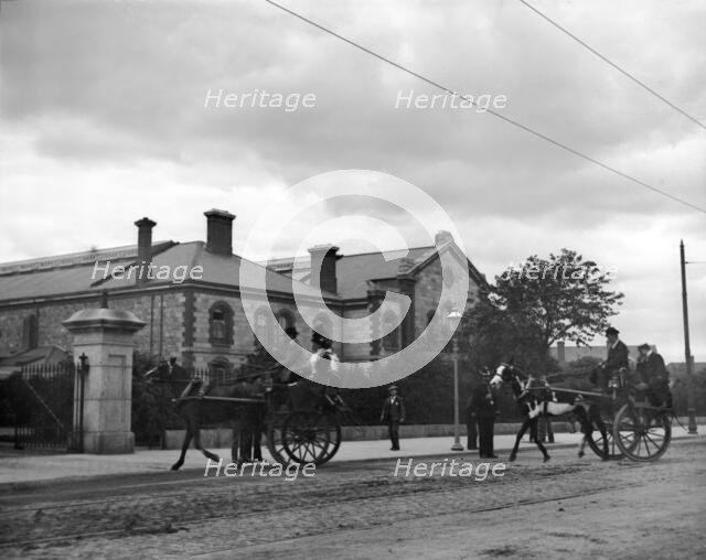 Street scene with horse carriages - possibly Ireland, 1898. Creator: Robert Augustus Henry L'Estrange.