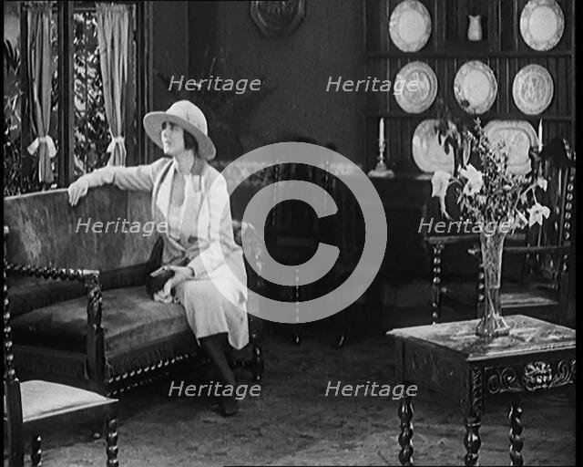 A Female Civilian Modelling a Two Piece Suit and Hat Sitting on a Sofa by a Window in a Draw... 1920 Creator: British Pathe Ltd.